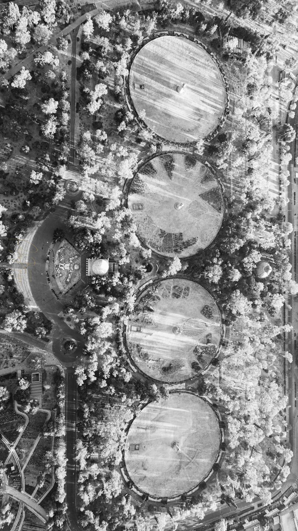 Aerial photo showcasing circular water treatment structures surrounded by trees.